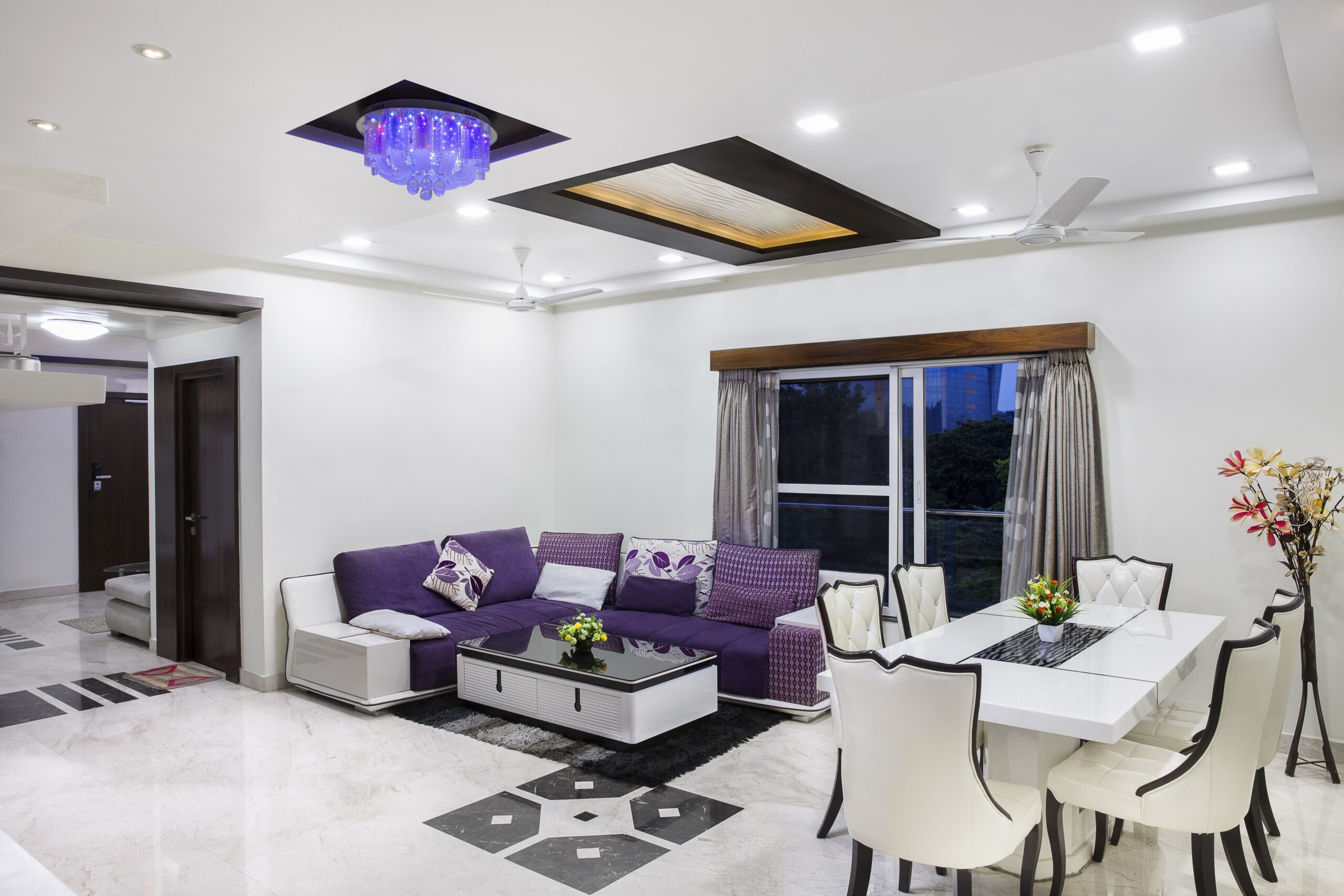 A living room with purple furniture and a ceiling fan that requires commercial cleaning services.