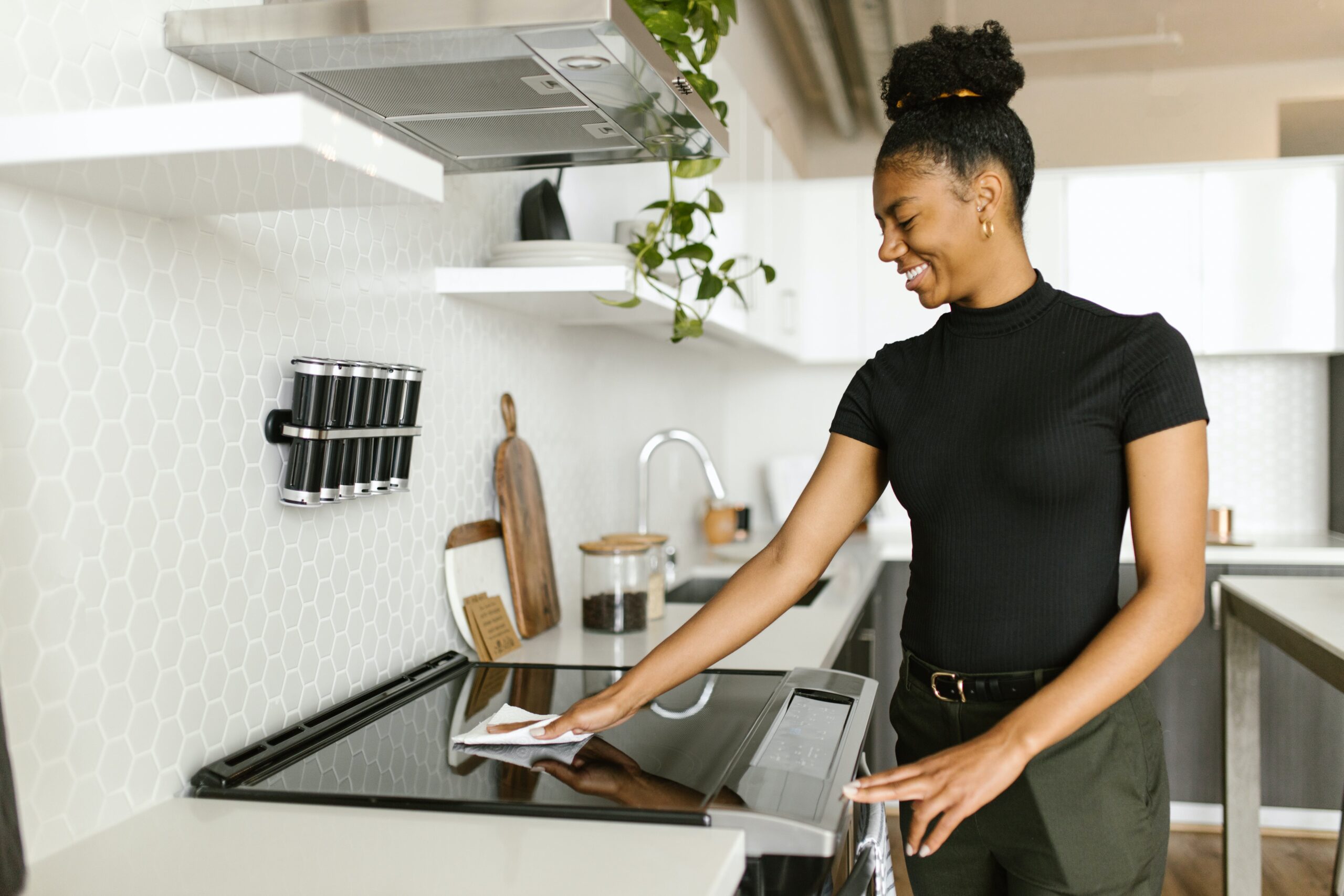 A woman performing seasonal cleaning on the stove in her kitchen.