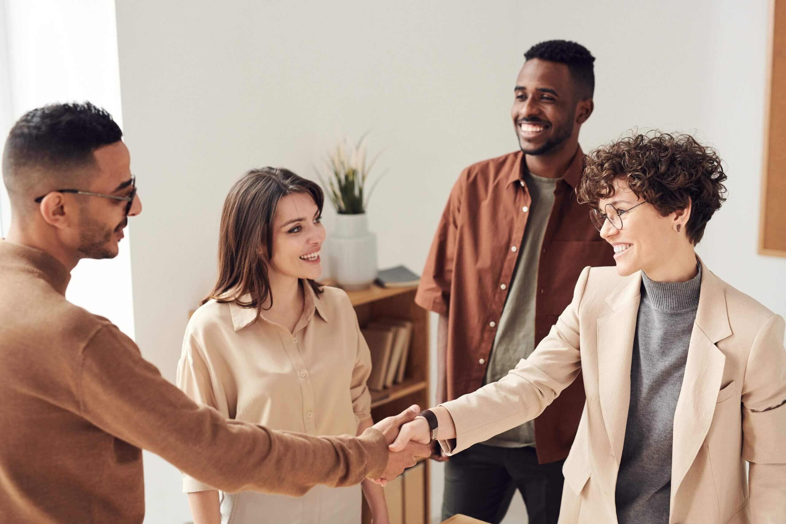 A group of people participating in a referral program, shaking hands in an office.